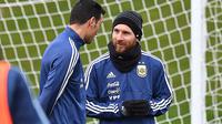 Lionel Messi (kanan) berdiskusi dengan rekannya saat sesi latihan di City Football Academy, Manchester, (20/3/2018). Argentina akan melawan Italia pada laga persahabatan di Etihad Stadiu. (AFP/Anthony Devlin)