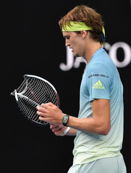 Petenis Jerman, Alexander Zverev memegang raketnya yang rusak seusai menghadapi petenis Korea Selatan, Chung Hyeon di turnamen Australia Terbuka, 20 Januari 2018. Raket tersebut bengkok dan tidak dapat digunakan lagi setelah dibanting. (SAEED KHAN/AFP)