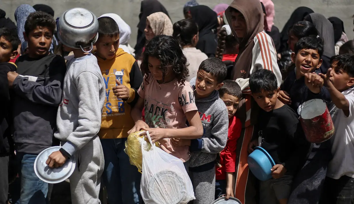 Mereka membawa piring dan wadah seadanya untuk menampung makanan gratis yang disediakan oleh dapur umum tersebut. (Eyad BABA/AFP)
