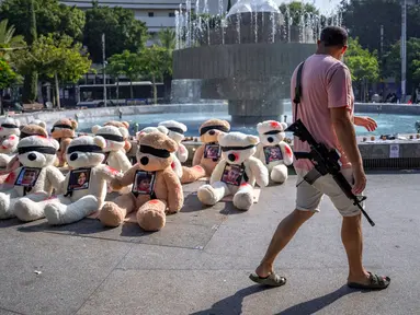 Seorang tentara Israel yang sedang tidak bertugas berjalan melewati instalasi boneka beruang raksasa dengan mata tertutup dan dihiasi foto warga Israel yang ditawan di Gaza di Tel Aviv, Israel, Rabu (25/10/2023). Instalasi tersebut dimaksudkan untuk menarik perhatian lebih dari 200 orang yang diculik oleh militan Hamas dalam serangan lintas batas pada 7 Oktober 2023. (AP Photo/Oded Balilty)