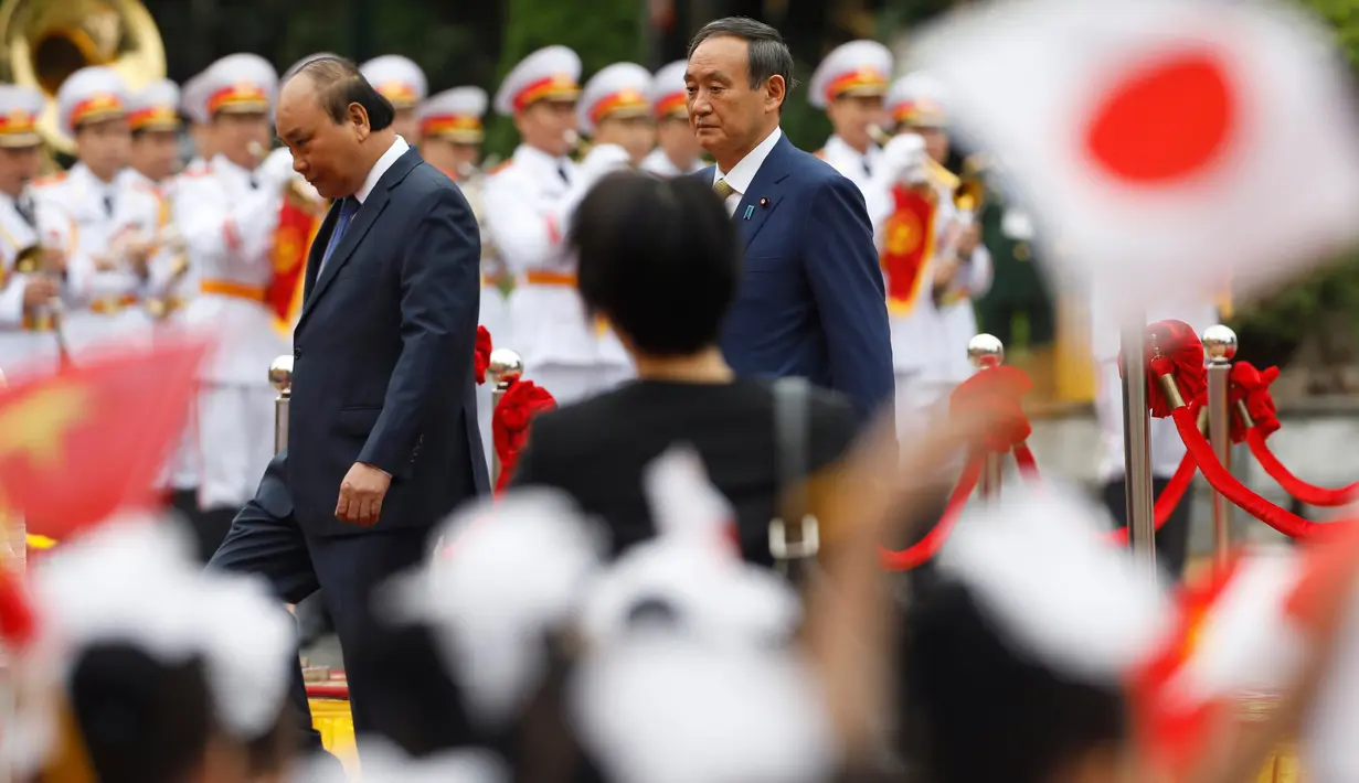 PM Jepang, Yoshihide Suga (kanan) bersama PM Vietnam, Nguyen Xuan Phuc saat upacara penyambutan tamu negara di Istana Kepresidenan, di Hanoi, Vietnam, Senin (19/10/2020). Yoshihide Suga melakukan kunjungan resmi ke Vietnam hingga 20 Oktober 2020. (Kham/Pool Photo via AP)