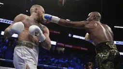 Pukulan jabs Floyd Mayweather Jr. mendarat wajah kanan Conor McGregor pada gelaran Tinju Dunia super welterweight boxing di MGM Arena, Las Vegas, (26/8/2017). Mayweather menang TKO atas McGregor. (AP/Isaac Brekken)