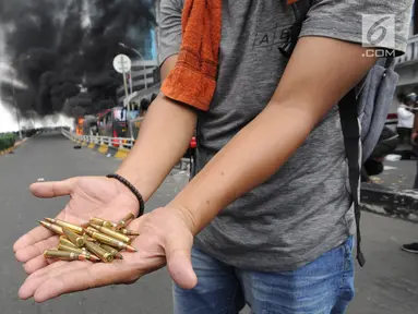 Seorang warga menunjukkan peluru dari kendaraan Polisi yang terbakar di Jalan Brigjen Katamso, Slipi, Jakarta, Rabu (22/5/2019). Belum diketahui penyebab terbakarnya dua bus yang terparkir bersama bus polisi lainnya dilokasi tersebut. (merdeka.com/Arie Basuki)