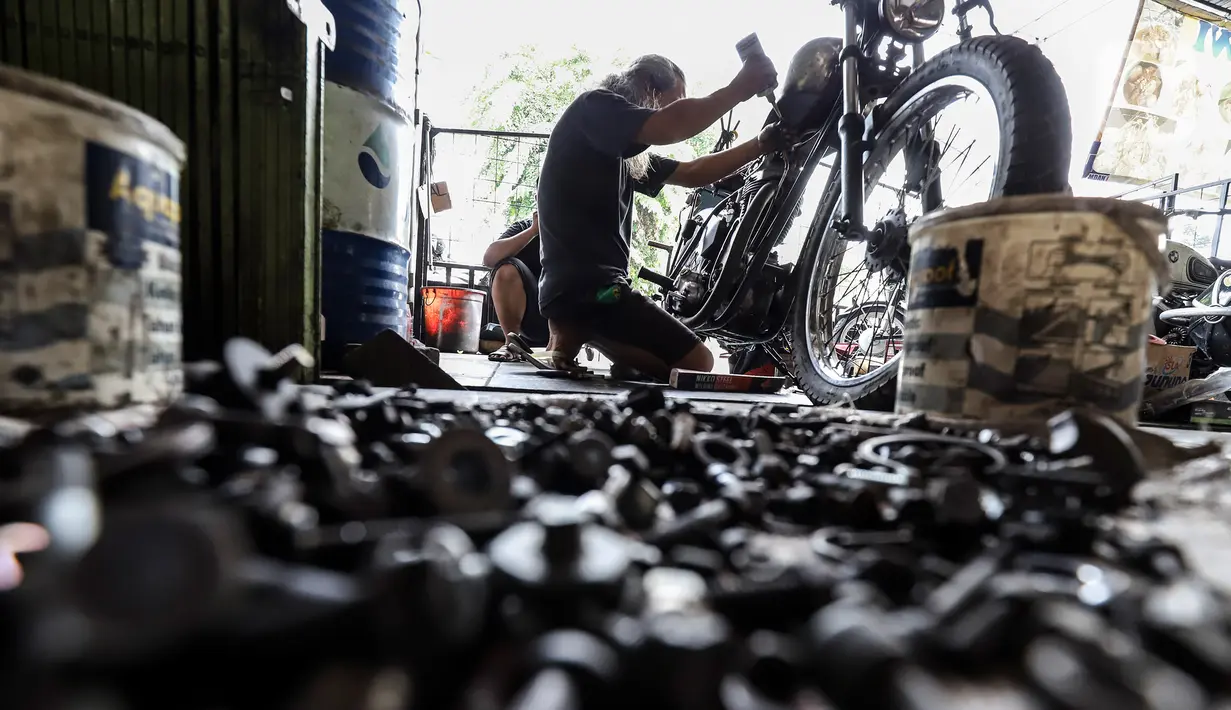 Pegawai bengkel motor custom menyelesaikan perakitan sepeda motor modifikasi di Classic Batavia Garage, Jakarta Selatan, Selasa (22/6/2021). Pandemi covid-19, bengkel Classic Batavia Garage kebanjiran jasa service dan modifikasi motor-motor sesuai dengan pesanan pelanggan. (Liputan6.com/Johan Tallo)