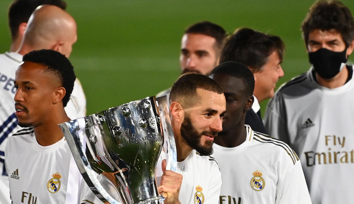 Striker Real Madrid, Karim Benzema, mengangkat trofi juara La Liga usai mengalahkan Villrreal pada laga lanjutan pekan ke-37 di Estadio Alfredo Di Stefano, Jumat (17/7/2020) dini hari WIB. Real Madrid menang 2-1 atas Villarreal. (AFP/Gabriel Bouys)