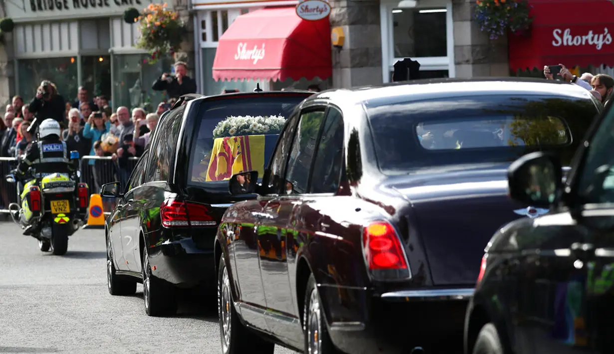 Warga berbaris saat mobil yang membawa peti berisi jenazah Ratu Elizabeth II melintas di Ballater, Skotlandia, Minggu (11/9/2022). Jenazah Ratu Elizabeth II diberangkatkan dari Kastil Balmoral ke Istana Holyroodhouse di Edinburgh sebelum nantinya akan dipindahkan ke London. (AP Photo/Scott Heppell)
