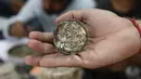 Seorang pria menunjukkan potongan uang kertas yang telah dibentuk, Ahmedabad, India (26/4). Ide kreatif ini berawal dari pemanfaatan mata uang kertas 500 dan 1.000 Rupee yang ditarik pemerintah India pada 2016 silam. (AFP PHOTO/SAM PANTHAKY)