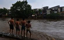 FOTO: Berbahaya! Aksi Nekat Anak-Anak Bermain di Tengah Derasnya Arus Kali Ciliwung