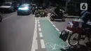 Pengguna jalan melintas di samping jalur sepeda yang di bongkar di kawasan Cikini, Jakarta, Selasa (19/11/2019). Jalur sepeda berumur 2 bulan tersebut dibongkar akibat proyek pelebaran trotoar. (Liputan6.com/Faizal Fanani)