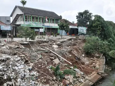 Kondisi tanah longsor di depan Gedung SDIT An-Najah, Kecamatan Cipayung, Kota Depok, Jawa Barat, Selasa (18/2/2020). Longsor di bantaran Kali Baru tersebut terjadi akibat terkikis hujan deras yang melanda pada awal tahun 2020 lalu. (merdeka.com/Iqbal Nugroho)