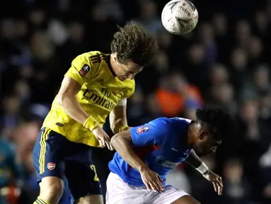 Bek Arsenal, David Luiz menyundul bola dibayangi pemain Portsmouth , Marcus Harness pada laga putaran lima Piala FA di Fratton Park, Senin (2/3/2020). Arsenal sukses membungkam tuan rumah Portsmouth dengan skor 2-0. (AP Photo/Kirsty Wigglesworth)