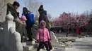 Warga berjalan di sebuah jembatan di Ditan Park di Beijing (1/2). Tahun Baru Imlek jatuh pada 16 Februari tahun ini, dengan perayaan yang berlangsung selama seminggu di China. (AFP Photo/Nicolas Asfouri)