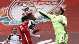 Kiper Fulham, Alphonse Areola (kanan) menepis bola dari ancaman gelandang Liverpool, Mohamed Salah dalam laga lanjutan Liga Inggris 2020/21 di Anfield Stadium, Minggu (7/3/2021). Fulham menang 1-0 atas Liverpool. (AFP/Phil Noble/Pool)
