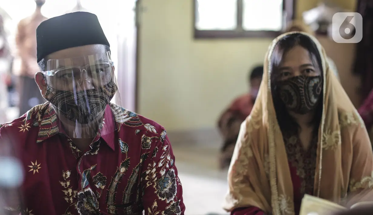 Pasangan pengantin menjalani prosesi akad nikah di KUA Pondok Pinang, Kebayoran Lama, Jakarta, Jumat (17/7/2020). Di masa PSBB transisi, pihak KUA menikahkan 8-10 pasangan per hari dengan mengikuti protokol kesehatan sesuai Surat Edaran Menteri Agama Nomor 15 Tahun 2020. (Liputan6.com/Johan Tallo)