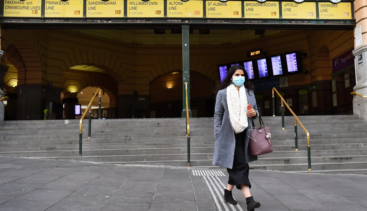 Komuter berjalan keluar dari Stasiun Flinders Street pada hari pertama wajib masker di tempat umum, di Melbourne, Kamis (23/7/2020). Penduduk kota terpadat kedua di Australia, Melbourne, diwajibkan mengenakan masker ketika meninggalkan rumah untuk mencegah penyebaran COVID-19. (William WEST/AFP)