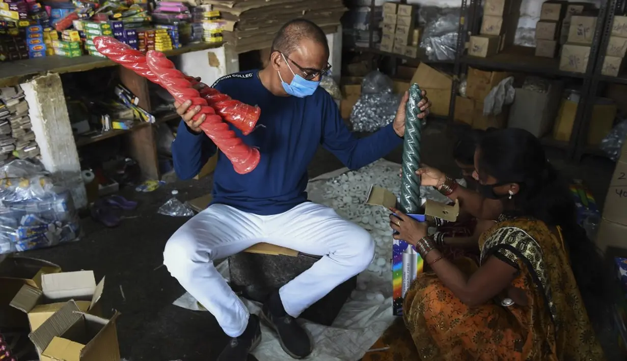 Pemilik pabrik Soheb Matcheswala mengemas lilin dengan seorang pekerja untuk didistribusikan jelang Festival Cahaya Diwali di pinggiran Ahmedabad, India, 4 November 2020. (SAM PANTHAKY/AFP)