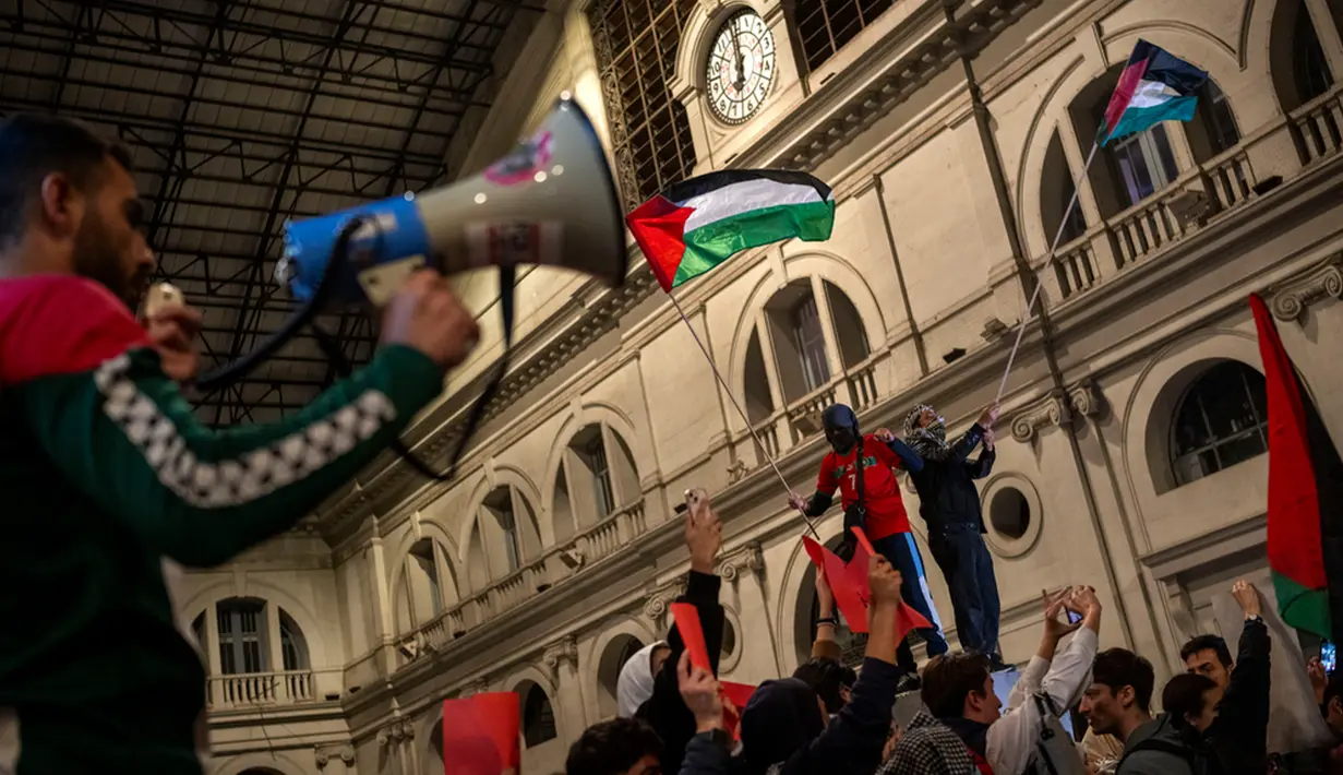 Demonstran pro-Palestina mengibarkan bendera Palestina dan meneriakkan slogan-slogan saat mereka menduduki stasiun kereta di Barcelona, Spanyol, Minggu (11/11/2023). (AP Photo/Emilio Morenatti)