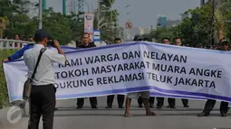 Nelayan membentangkan spanduk berisi penolakan reklamasi Teluk Jakarta di kawasan Muara Angke, Jakarta, Rabu (2/12). Mereka menolak keras proyek reklamasi pulau G karena dapat menghilangkan sumber kehidupan para nelayan. (Liputan6.com/Gempur M Surya)