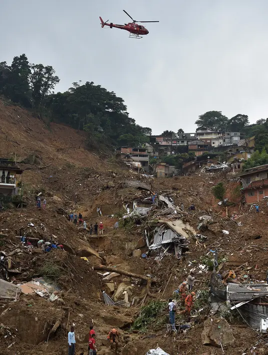 Helikopter tim penyelamat pemadam kebakaran melintasi area tanah longsor untuk mencari korban selamat di Petropolis, Brasil, 16 Februari 2022. Banjir skala besar menghancurkan ratusan properti dan merenggut sebanyak 34 nyawa di daerah tersebut. (CARL DE SOUZA/AFP)