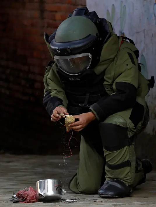 Anggota kepolisian memakai pakaian khusus terlihat serius menjinakkan bom yang ditemukan di sekitar sebuah sekolah di Kathmandu, Nepal, Selasa (20/9). Tidak ada korban jiwa dengan kejadian ini. (REUTERS/Navesh Chitrakar)