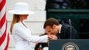 Presiden Prancis Emmanuel Macron mencium tangan Istri Presiden AS Donald Trump, Melania Trump saat upacara menyambut kedatangan tamu negara di Gedung Putih, Washington (24/4). (AP Photo/Evan Vucci)
