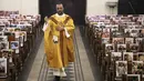 Pastor Katolik Georges Nicoli merayakan misa Kamis Putih disiarkan langsung di Facebook, dengan foto-foto jemaat yang ditempel dibangku di gereja Notre Dame De Lourdes di Bastia, di pulau Korsika Mediterania, Prancis (9/4/2020). (AFP/Pascal Pochard-Casabianca)