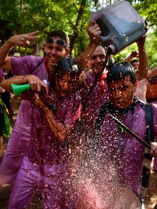 Orang-orang bersuka ria dalam perang anggur di Haro, Spanyol utara, Sabtu (29/6/2019). Ratusan orang berpartisipasi dalam pertempuran musim panas yang terkenal ini dengan menumpahkan ribuan liter anggur merah atau wine ke tubuh peserta satu sama lain. (AP/Alvaro Barrientos)