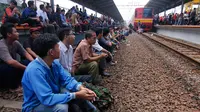 Sejumlah calon penumpang kereta menduduki rel untuk menutup jalur kereta api di stasiun Bekasi, Jawa Barat. (ANTARA FOTO/Hafidz Mubarak)