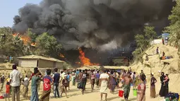 Pengungsi Rohingya menyaksikan asap membubung menyusul kebakaran di kamp pengungsi Rohingya di Balukhali, Bangladesh selatan (22/3/2021). Sejumlah orang meninggal dan 20 ribu orang mengungsi akibat kebakaran hebat di kamp pengungsi. (AP Photo/Shafiqur Rahman)