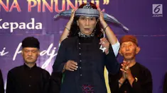 Menteri Kelautan dan Perikanan Susi Pudjiastuti  dipakaikan totopong saat pertemuan dengan Masyarakat Adat Jawa Barat di Jakarta, Rabu (19/3). Dalam acara itu, Susi menerima gelar kehormatan dari masyarakat adat Jawa Barat. (Liputan6.com/Johan Tallo)