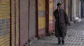 Pria Kashmir berjalan di luar pasar tertutup di Srinagar, Kashmir yang dikuasai India, Sabtu (15/1/2022). Pihak berwenang di bagian Kashmir India mengumumkan pembatasan penuh pergerakan yang tidak penting selama akhir pekan di seluruh negara bagian untuk mengekang COVID-19. (AP Photo/Dar Yasin)