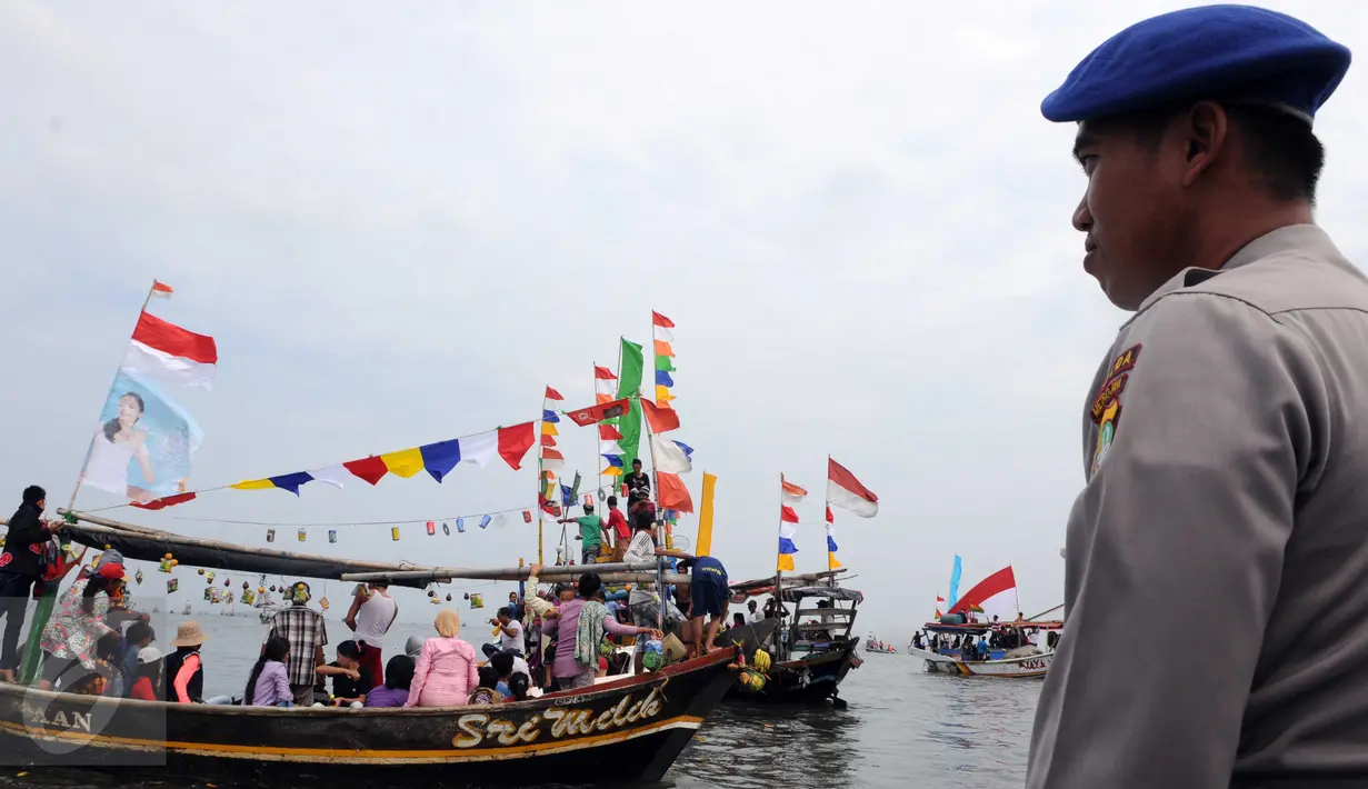 Seorang petugas mengamati saat para nelayan bersama keluarganya mengikuti sedekah bumi Nadran di Muara Angke, Jakarta, Minggu (13/12). Tradisi ini sebagai ungkapan rasa syukur kepada Tuhan YME atas hasil laut yang diperoleh. (Liputan6.com/Helmi Afandi)