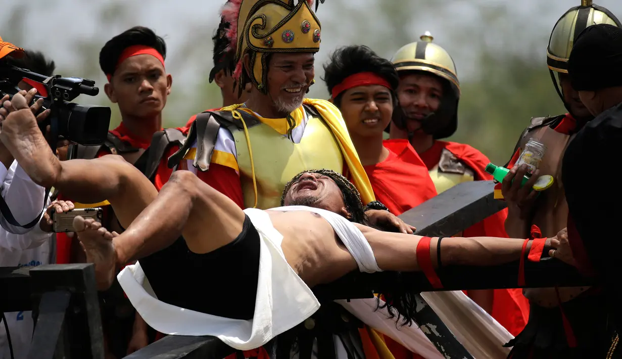 Ekspresi Ruben Enaje (kanan) saat tangannya dipaku ke tiang salib di Pampanga, Filipina, Jumat (30/3). Aksi tersebut dilakukan dalam rangka visualisasi penderitaan Yesus Kristus menyambut Jumat Agung. (AP Photo/Aaron Favila)