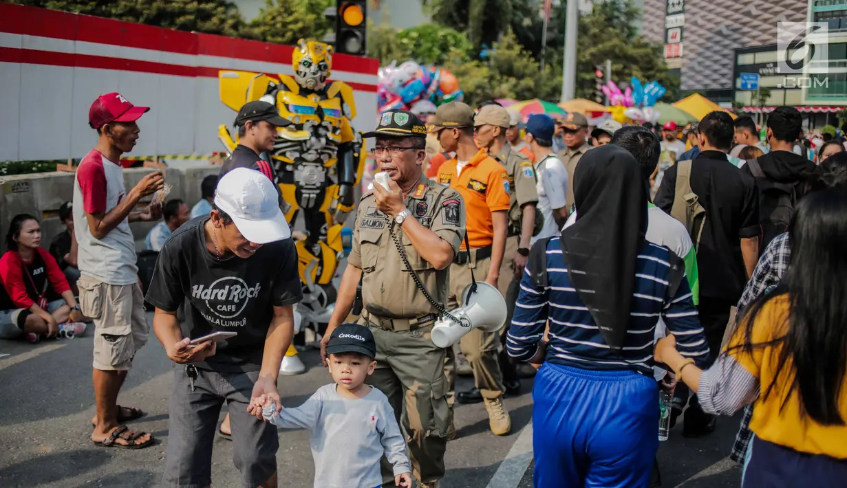Petugas Satpol PP melakukan sosialisasi saat menertibkan PKL di kawasan car free day (CFD), Bundaran HI, Jakarta, Minggu (4/8/2019). Penertiban dilakukan karena keberadaan PKL membuat tidak nyaman pengunjung CFD yang ingin berolahraga, berorasi, atau sekadar jalan-jalan. (Liputan6.com/Faizal Fanani)