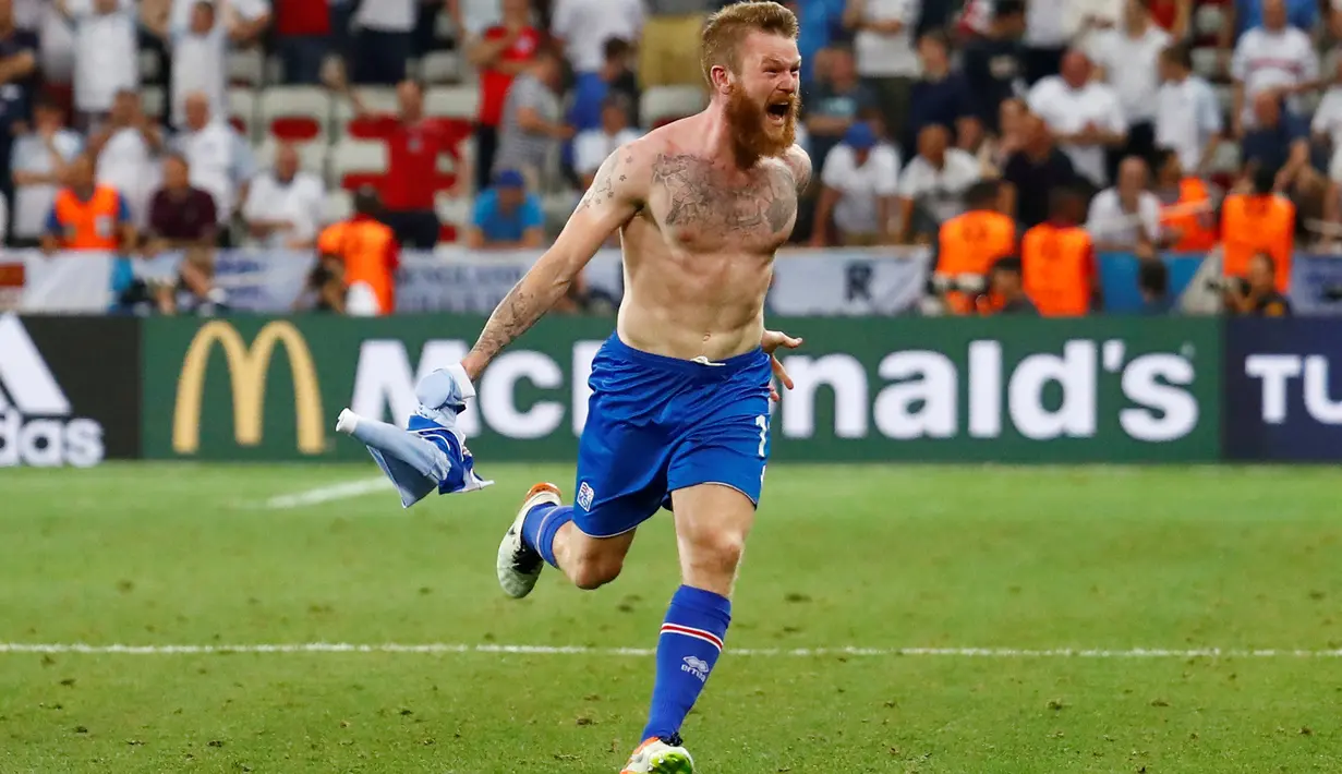 Kapten timnas Islandia, Aron Gunnarsson merayakan kemenangan Islandia atas Inggris dengan cara melepas jerseynya, Selasa (28/6) dini hari. Islandia membuat kejutan besar dengan menyingkirkan Inggris dari Piala Eropa 2016. (REUTERS/Michael Dalder)