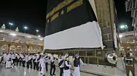 Petugas saat mengganti kain penutup Ka'bah (Kiswah) dengan yang baru di Masjidil Haram, kota suci Makkah, Arab Saudi (18/7/2021). Menjelang puncak ibadah haji 1442 H, petugas Masjidil Haram melakukan penggantian kain penutup Ka'bah lama dengan Kiswah yang baru. (AFP Photo)