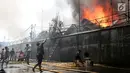 Warga mencoba memadamkan api yang membakar pemukiman padat penduduk di kawasan Manggarai, Jakarta, Rabu (10/7/2019). Sebanyak 27 Unit mobil pemadam kebakaran diterjunkan untuk memadamkan api yang melanda pemukiman di dekat Stasiun Manggarai tersebut. (Kapanlagi.com/Budy Santoso)