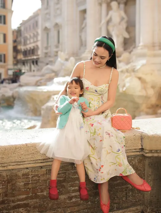 Seperti potret ini, Shandy Aulia tampil anggun dibalut spaghetti strap dress motif floral dominasi warna putih.