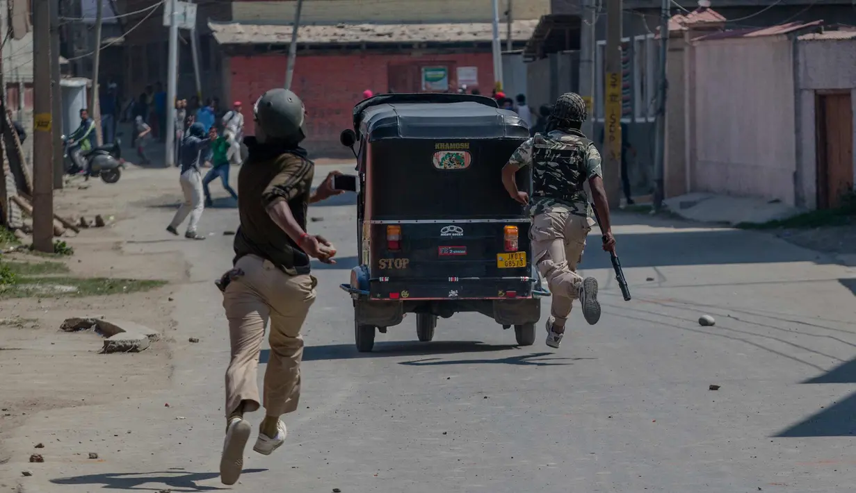 Seorang tentara paramiliter India membawa batu selama bentrok dengan pengunjuk rasa selama protes terhadap pembunuhan pemberontak di Srinagar, Kashmir yang dikuasai India, (1/4). (AP Photo / Dar Yasin)