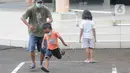 Pasien Covid-19 menemani seorang anak bermain di halaman Graha Wisata Ragunan, Jakarta, Selasa (15/6/2021). Pemprov DKI memfungsikan kembali Graha Wisata Ragunan sebagai tempat isolasi warga terpapar COVID-19 kategori OTG sejak pekan lalu dan saat ini merawat 117 pasien. (merdeka.com/Arie Basuki)