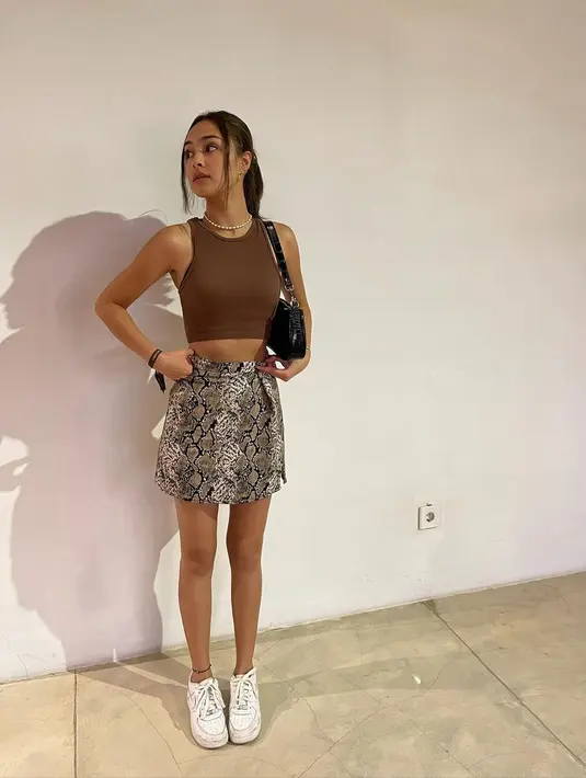 Tampil trendi dengan racerback tank top, mini skirt bercorak snake skin, dibarengi kalung bikin gaya chic. [IG: caitlinhalderman].