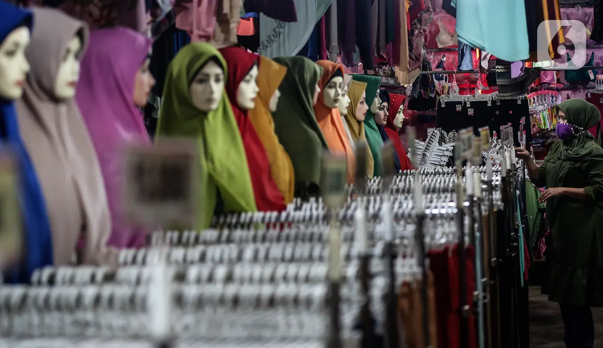 Pedagang gamis dan baju anak menunggu pembeli di kiosnya di pasar Parung, Bogor, Jawa Barat, Kamis (18/2/2021). Dampak pandemi COVID-19 yang berkepanjangan pedagang mengaku omset penjualan gamis dan baju anak turun 85 persen semenjak awal tahun lalu hingga sekarang. (Liputan6.com/Johan Tallo)