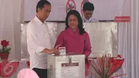 Presiden Joko Widodo (Jokowi) didampingi Ibu Negara, Iriana, memasukkan kertas suara ke kotak suara usai menggunakan hak pilihnya dalam Pilkada DKI 2017 putaran kedua di TPS 04 Gambir, Jakarta, Rabu (19/4).  (Liputan6.com/Angga Yuniar)