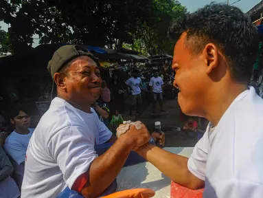 Pedagang pasar saat mengikuti lomba panco antar pedagang dan pengunjung pasar di Pasar Rakyat Ciseeng, Bogor, Sabtu (20/7/2024). (merdeka.com/Arie Basuki)