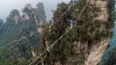 Dua kontestan berpakaian karakter Avatar berpacu sepanjang slackline di Pegunungan Huangshizhai di Zhangjiajie, Hunan, China, Minggu (23/12). Aksi tersebut dilakukan di Situs Warisan Dunia Wulingyuan atau Pegunungan Melayang. (STR/AFP)