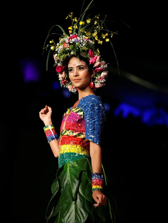 Model berpose di atas catwalk mengenakan busana yang berwarna-warni lengkap dengan aksesoris kepala yang menyerupai mahkota dari aneka bunga saat pergelaran Biofashion di Cali, Kolombia (19/11). (Reuters/Jaime Saldarriaga)