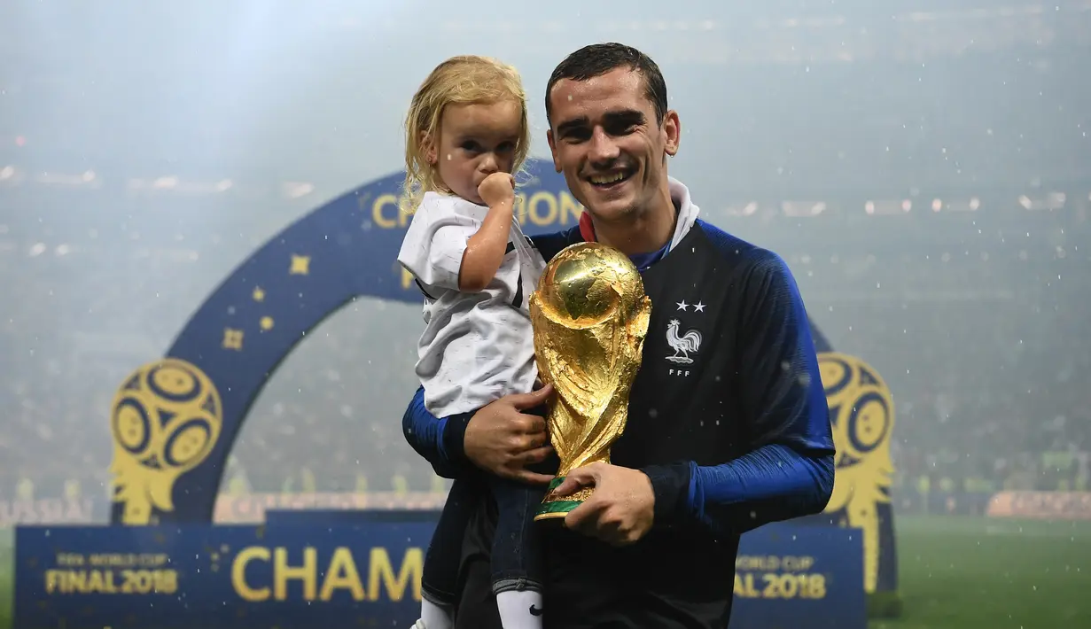 Pemain depan Prancis, Antoine Griezmann berpose dengan putrinya sambil membawa trofi Piala Dunia di Stadion Luzhniki, Moskow, Rusia, 15 Juli 2018. Griezmann masuk dalam kandidat pemain terbaik FIFA 2018. (AFP FOTO/FRANCK FIFE)