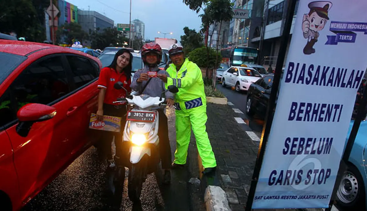 Seorang petugas bersama Pandu Jalan Fullo melakukan sosialisasi tertib berlalu lintas di kawasan perempatan Cideng, Jakarta, Senin (23/2). (Liputan6.com/Johan Tallo)