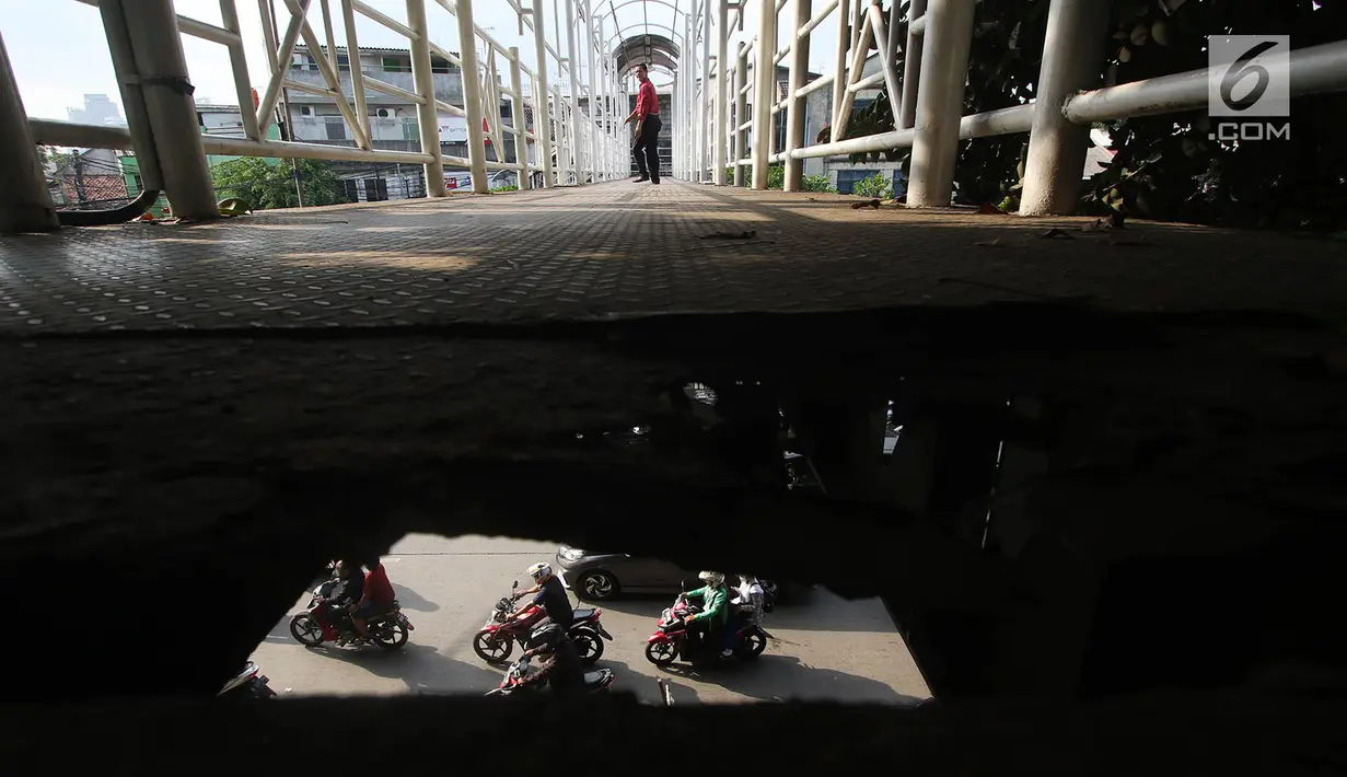 Pejalan kaki melintasi Jembatan Penyeberangan Orang (JPO) dengan kondisi bolong, berkarat dan tanpa atap di Petamburan, Tanah Abang, Jakarta, Selasa (24/10). Kondisi jembatan ini cukup mengganggu kenyamanan pejalan kaki. (Liputan6.com/Immanuel Antonius)