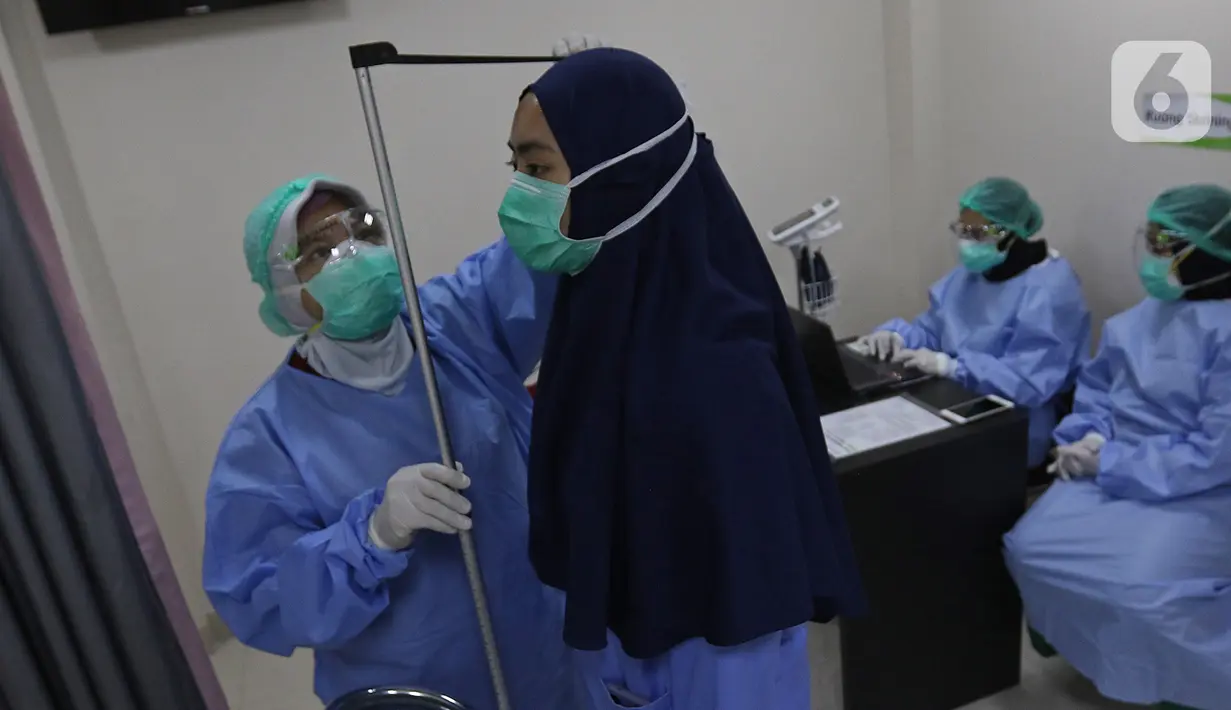 Petugas medis (kiri) mengukur tinggi badan seorang tenaga kesehatan (kiri) saat skrining kesehatan dalam simulasi pemberian vaksin COVID-19 di RSIA Tambak, Jakarta, Rabu (13/10/2021). Vaksinasi COVID-19 akan dilakukan oleh Pemprov DKI Jakarta pada 15 Januari 2021. (Liputan6.com/Herman Zakharia)